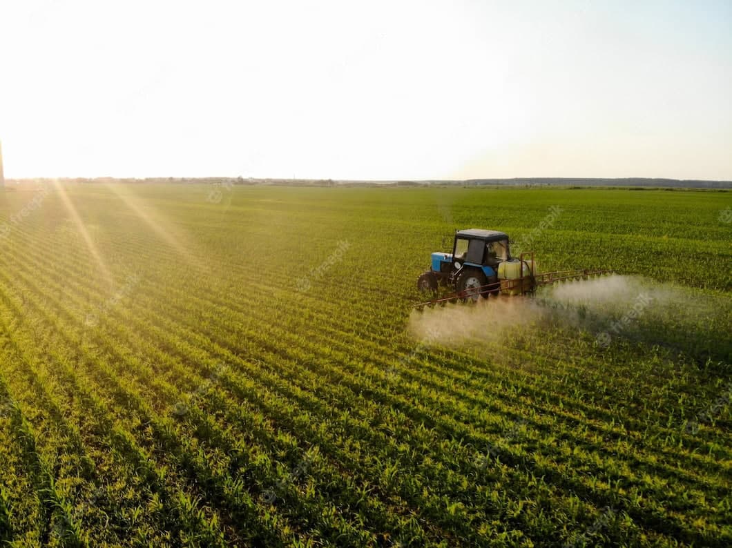 Tractor spraying crops in a green field