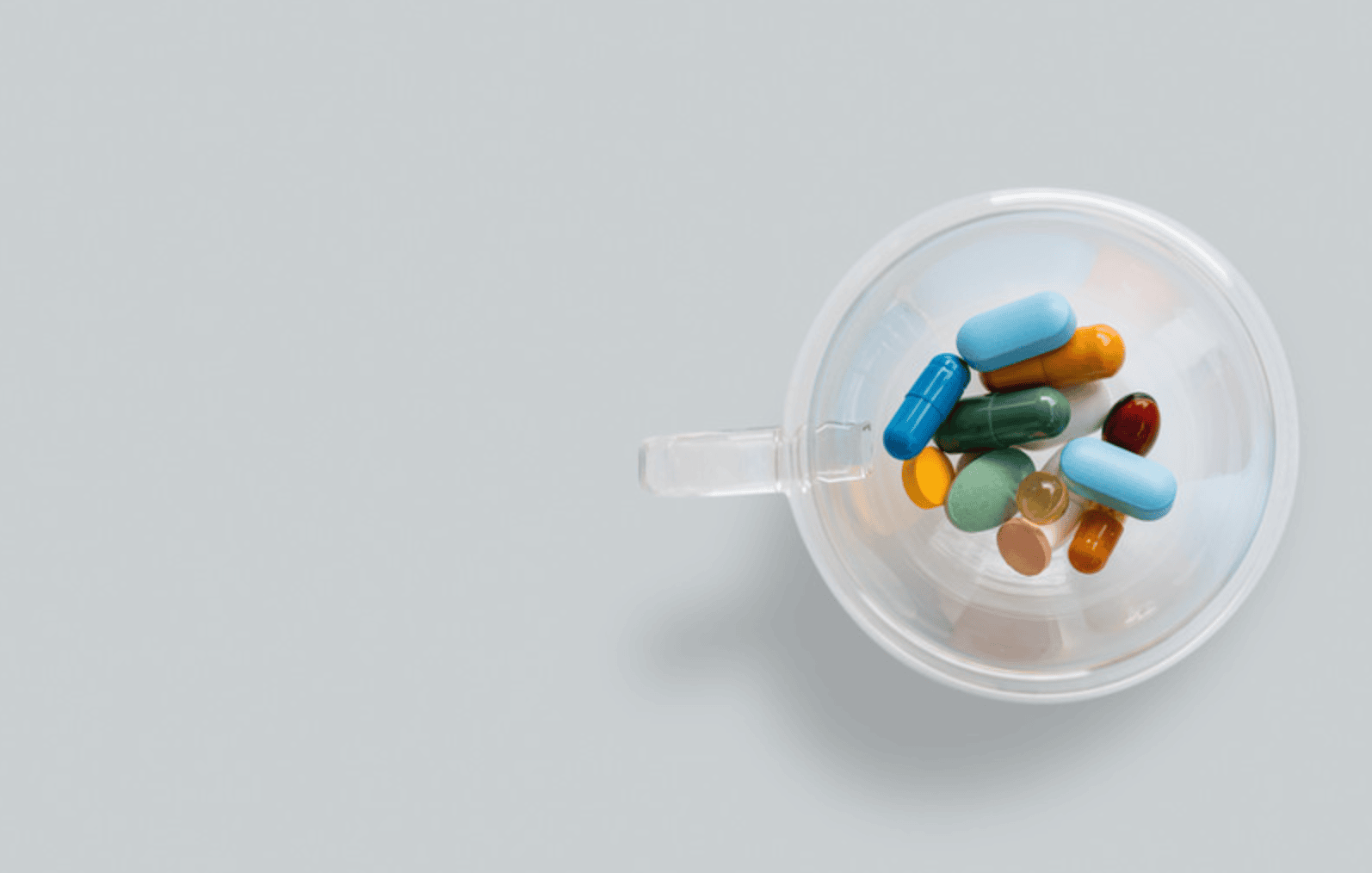 Colourful tablets and capsules in a clear cup